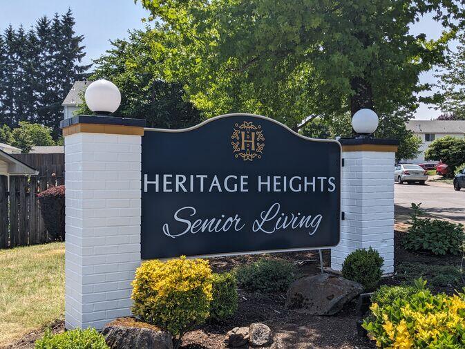 Custom monument sign for Heritage Heights Senior Living featuring dark blue panels with white lettering, mounted between two white brick columns